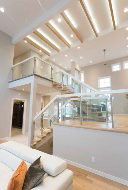Access to the home’s upper level is attained via a magnificent open-riser oak staircase that winds its way upward beneath six lit oak beams (from Winder Woodworks) that mimic it above. The staircase (also built by Winder Woodworks), features glass insert panels and stainless steel posts from SSG Notion, a division of Fort Rouge Glass.